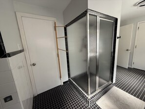 Bany amb plat de dutxa, terra emblanquida i una porta blanca.