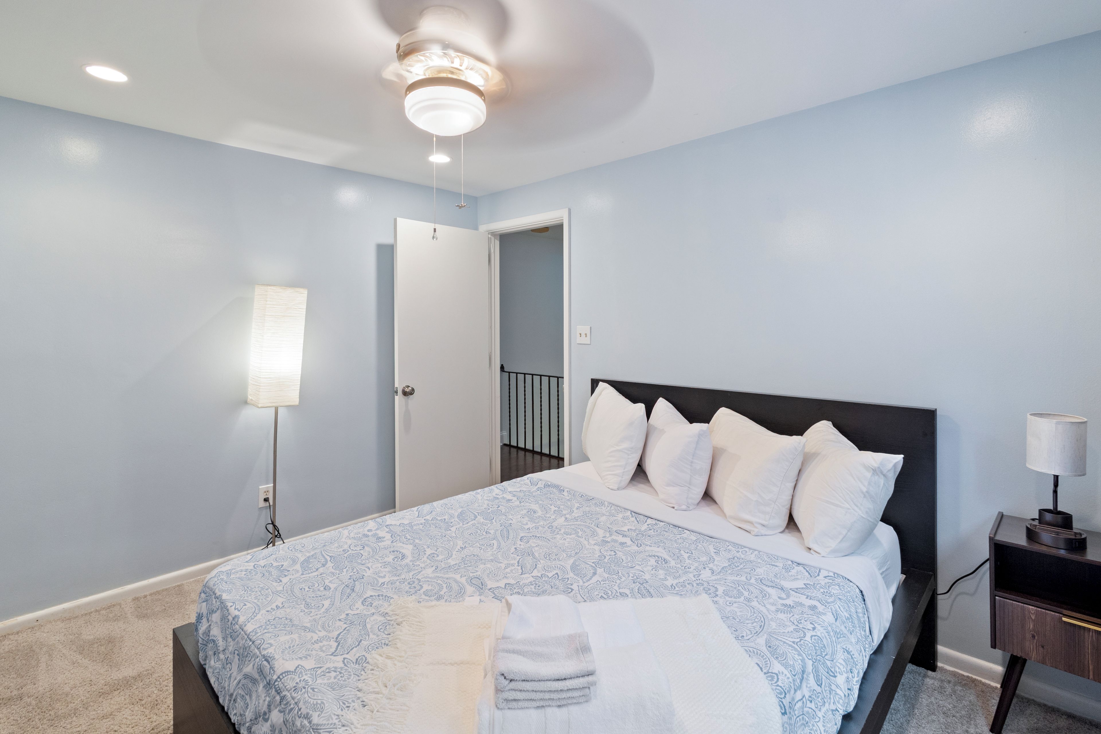 Un dormitorio con cama, mesita de noche, lámpara y lámpara de techo.