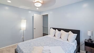 Un dormitorio con cama, mesita de noche, lámpara y lámpara de techo.
