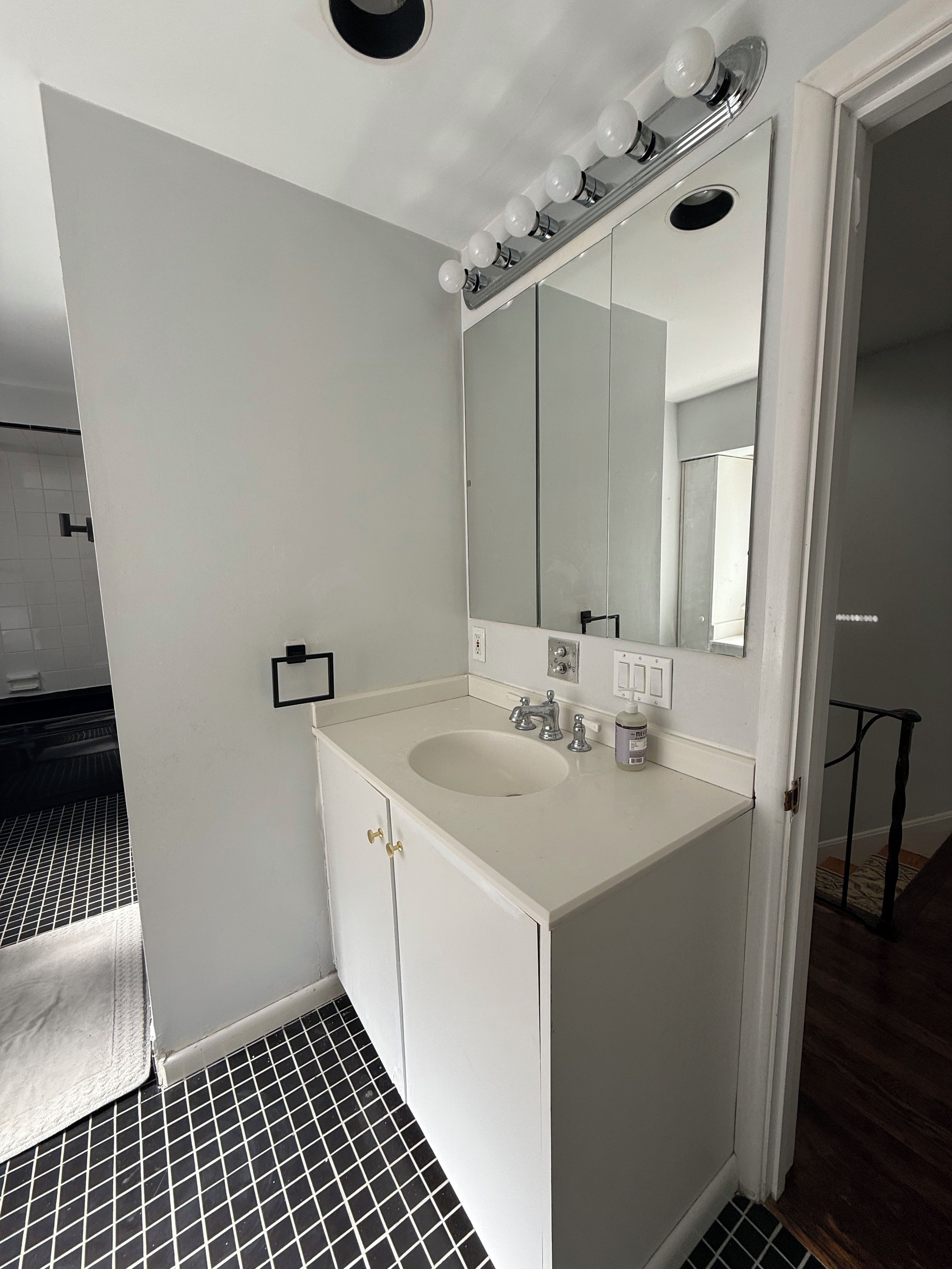 Une salle de bain avec un meuble-lavabo blanc, un grand miroir et un évier.