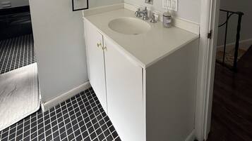 Une salle de bain avec un meuble-lavabo blanc, un grand miroir et un évier.
