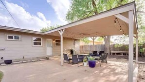 Un patio couvert avec des meubles d’extérieur, une table et des chaises.