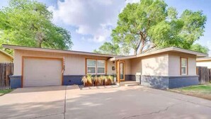 Une maison à deux étages avec un garage, une véranda à l’avant ornée de plantes et une allée.