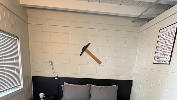 Une chambre à coucher comprenant un lit, une table de chevet, un porte-serviettes fixé au mur et une fenêtre avec des stores.