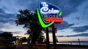 Une enseigne au néon indiquant « The Cedars Motel », avec une autre enseigne en dessous indiquant « Complet ».