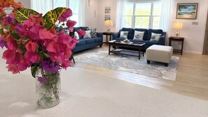 Un salón con sofá, mesa de centro y un jarrón decorativo con flores.