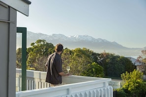 Une personne se tient sur un balcon d’où l’on peut admirer un paysage montagneux.