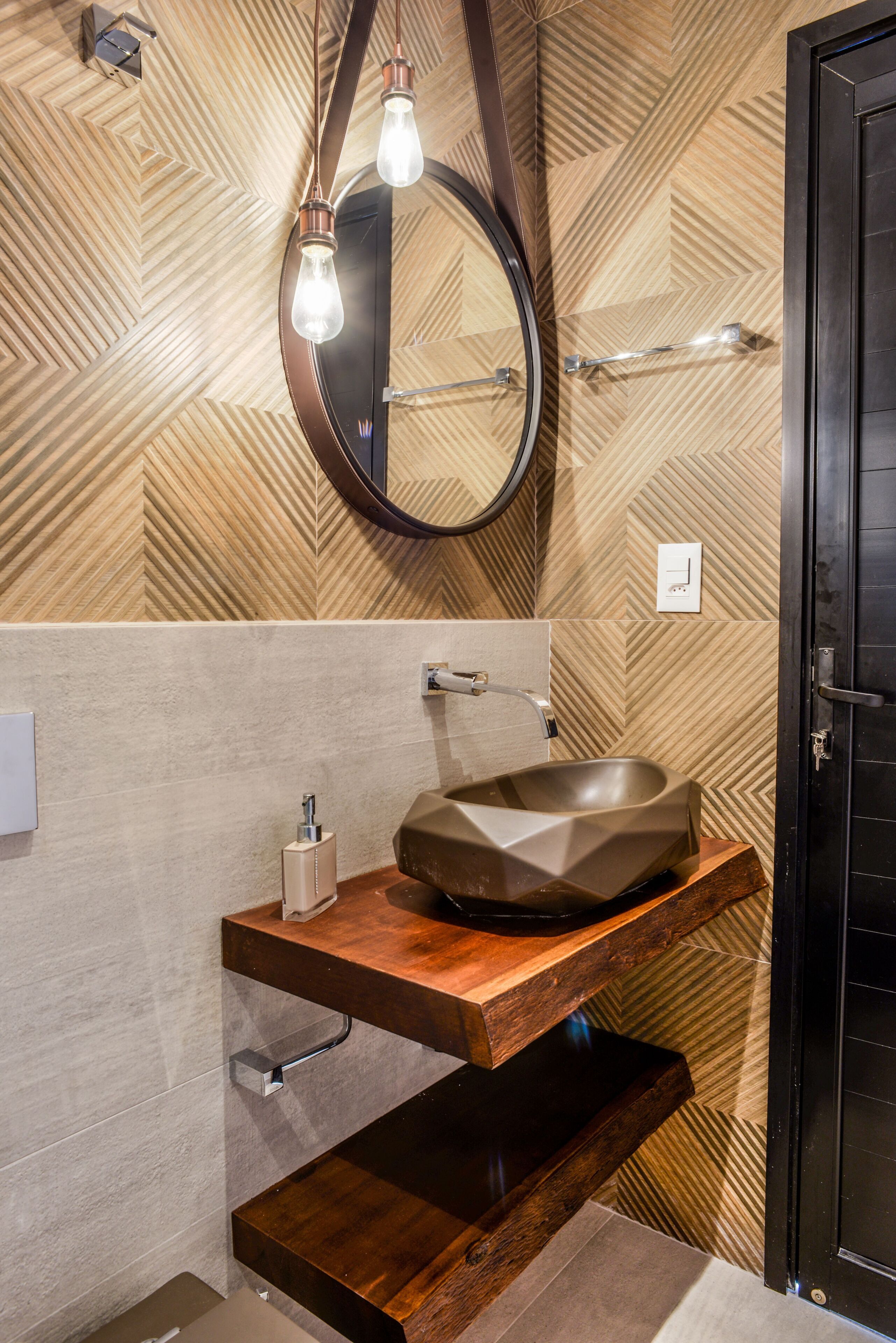 A bathroom with a wooden vanity, a round mirror, and a modern sink.