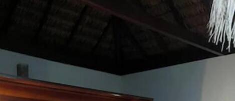 A bed with a wooden headboard, a wall with a decorative headpiece, and a round rug.