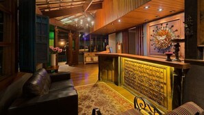 A lobby with a wooden ceiling, a reception desk, a sofa, and a patterned rug.