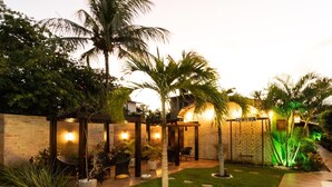 A well-lit outdoor patio area with a brick wall, palm trees, and a seating area with chairs and tables.