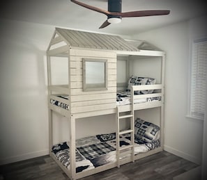 Un lit superposé avec un toit en pente et un ventilateur de plafond.
