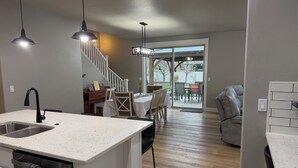 Una cucina moderna con isola integrata, un'area pranzo con tavolo e sedie, una scala e vista all'esterno.