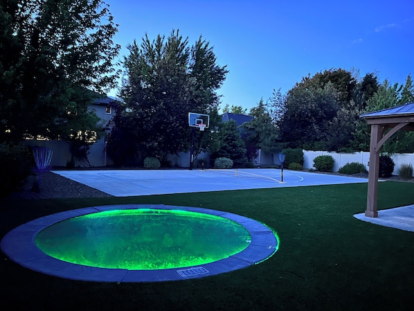 Un cortile con un canestro da basket, un trampolino e un gazebo.