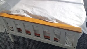 Ein Einzelbett mit weißer Bettwäsche, einem Holz-Kopfteil und einem weißen Kissen.