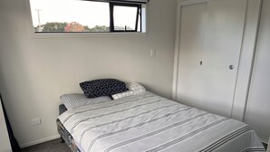 Ein Schlafzimmer mit Bett, Fenster, Tür und Teppichboden.