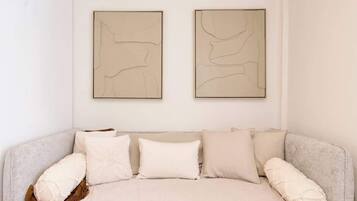 A neutral-toned room with a sofa, two abstract wall art pieces, and a brown throw blanket.