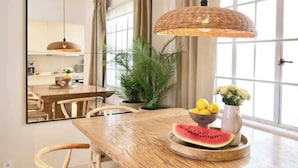 A dining area with a wooden table, a mirror, a wicker pendant light, and a bowl of fruit. - Nala - Increíble 3BR en CDMX, Col. Cuauhtémoc (Mexico City)