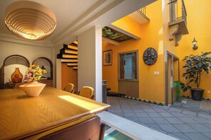 A dining area with a wooden table, chairs, a vase with flowers, a hanging light fixture, and a staircase leading to an upper level. - Casa del Sol. 4 bedrooms + garden | 8 guests (Mexico City)
