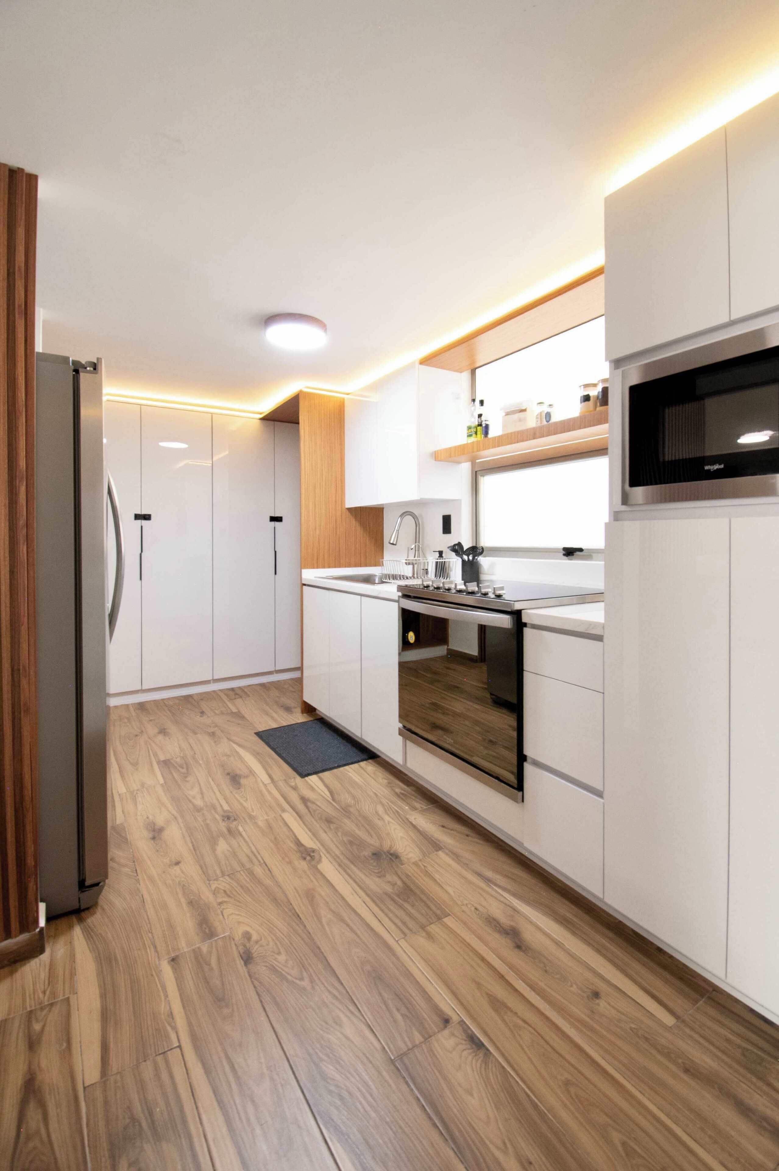 Une cuisine moderne avec des meubles blancs, un four encastré et un micro-ondes.