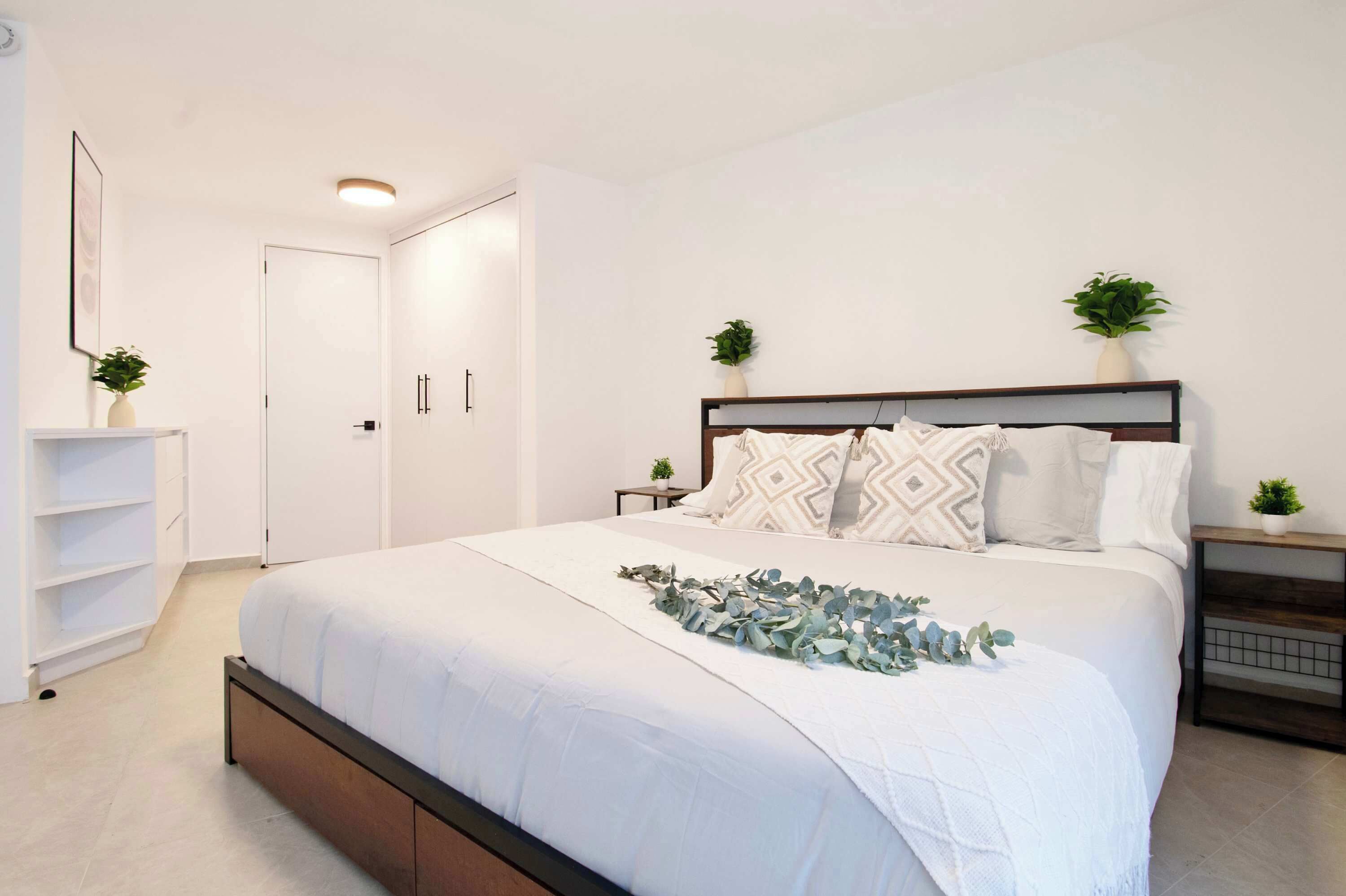 Une chambre à coucher bien rangée, avec un lit, des tables de chevet, une armoire et une porte.