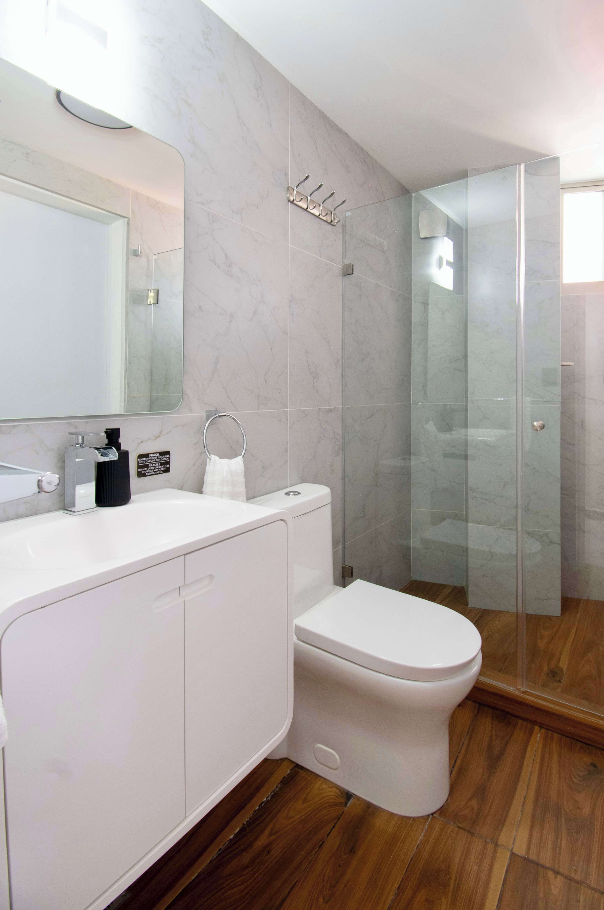 Une salle de bain moderne équipée de toilettes, d’un lavabo et d’une douche à parois de verre.
