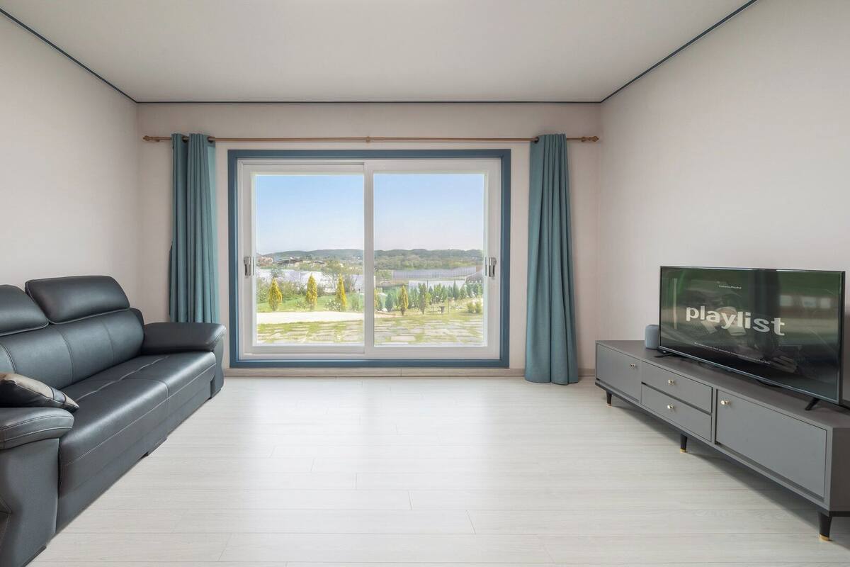 Ein modernes Wohnzimmer mit einer Couch, einem Flachbildfernseher und einer Glastür, die auf einen Balkon führt.