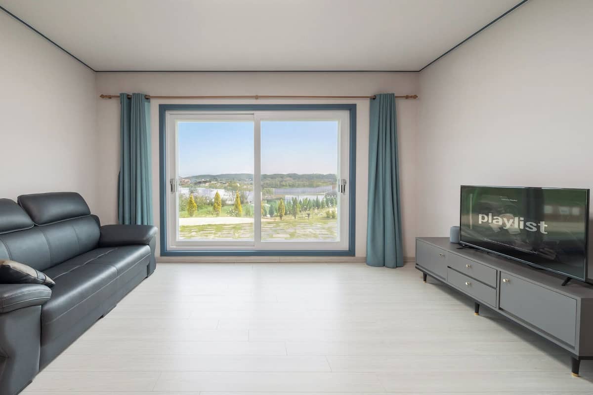 Un salon moderne avec un canapĂ©, un tĂ©lĂ©viseur Ă Ă©cran plat et une porte-fenĂȘtre coulissante donnant sur un balcon.