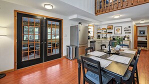 A dining area with a wooden table and chairs, a kitchen with appliances, and a balcony with a wooden railing.