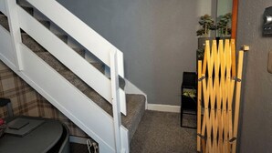 A staircase with white railings, a gray wall, and a small table with a plaid tablecloth. - 1BR Charming Cottage in Central Moffat (Moffatt)