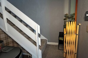 Eine Treppe mit weißen Geländern, einer grauen Wand und einem kleinen Tisch mit karierter Tischdecke.