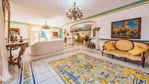 Eine geräumige Lobby mit einem gemusterten Boden, einer Chandelier, einem Sofa und einem Gemälde an der Wand.