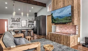 A modern living room with a wooden TV stand, a sofa, and a kitchen in the background.