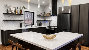 A modern kitchen with a large island, dark cabinetry, and pendant lighting. - Above the Clouds Luxury Retreat with Hot Tub and Epic Views (Morganton)