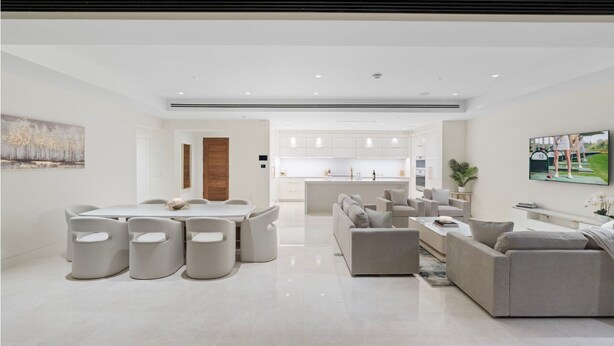A modern living room with a dining area, a kitchen in the background, and a large painting on the wall. - Luxury Brand-New Apartment with Pool-Ritz Resort (Paradise Valley)