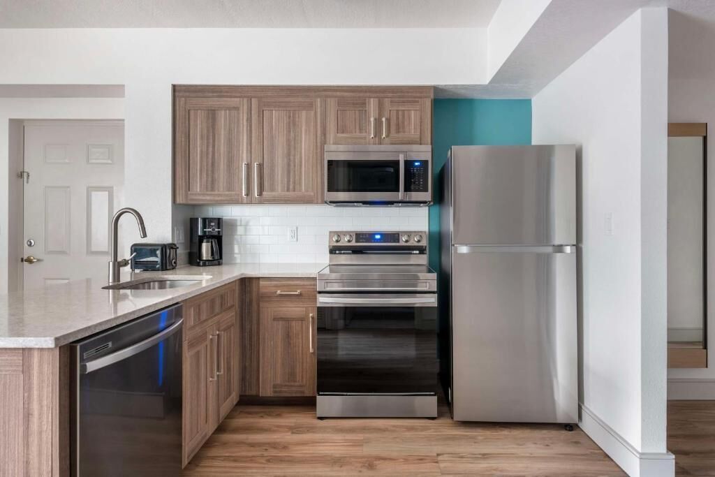 Una cocina moderna con gabinetes de madera, electrodomésticos de acero inoxidable y lavavajillas.