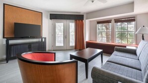 Ein modernes Wohnzimmer mit Flachbildfernseher, Deckenventilator, Sofa, Couchtisch und einem Fenster mit Vorhängen.