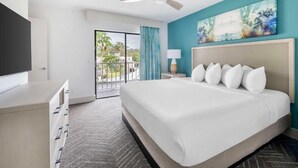Ein Hotelzimmer mit Bett, Fernseher, Deckenventilator, einem Bild und Blick ins Freie.