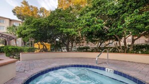 Ein Whirlpool mit einer 3 FT tiefen Markierung, umgeben von einer Ziegelterrasse, Bäumen und einem Gebäude im Hintergrund.