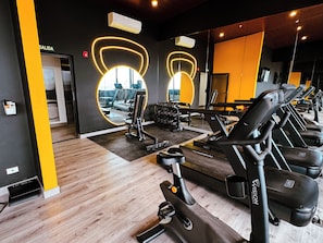 Un gimnasio con equipo de ejercicio, un espejo y una pared de acento amarillo.