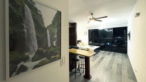 Interior moderno com área de jantar, ventoinha no teto e uma grande janela com vista para a cidade.