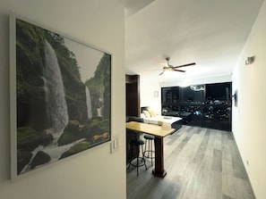 Un interior moderno con zona de comedor, ventilador de techo y un ventanal con vista a la ciudad.