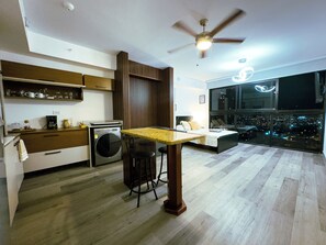 Una cocina moderna con lavadora, una zona de comedor con mesa y sillas, y un ventanal con vistas a la ciudad.