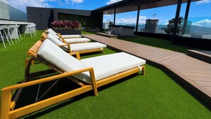 Terraço no telhado com espreguiçadeiras, área de refeições e vista para a cidade.