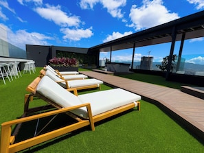 Una terraza en la azotea con tumbonas, zona de comedor y vistas panorámicas de la ciudad.