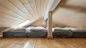 A loft bedroom with a sloped ceiling, wooden beams, and a skylight. - VillaVilla 956 - Marielyst, Lolland/Falster/møn (Væggerløse)
