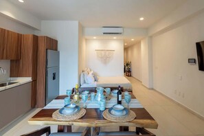 A modern kitchen with wooden cabinets, a built-in refrigerator, and a dining area with a wooden table set for two. - Maralma Bucerias 1 half Blocks from Beach Sleeps 4 (Bucerías)