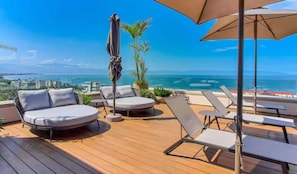 A deck with lounge chairs and a sofa, overlooking a coastal view. - Maralma Bucerias 1 half Blocks from Beach Sleeps 4 (Bucerías)