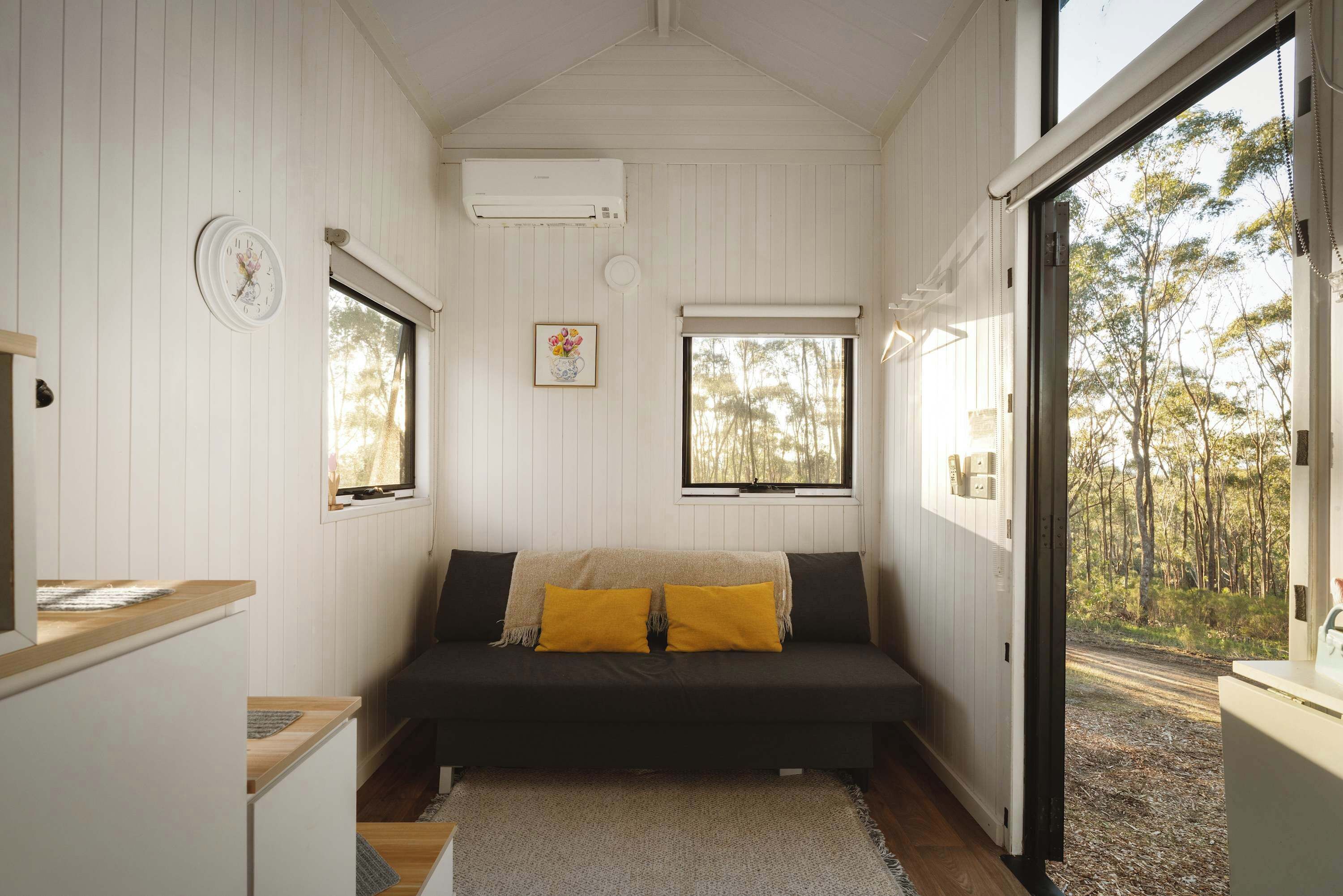 A cozy room with a bed, a clock, and a window with a view of trees.