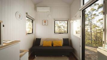 A cozy room with a bed, a clock, and a window with a view of trees.